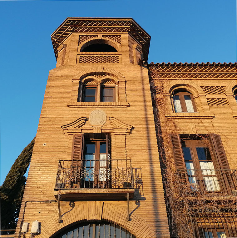 Torre de ladrillo del palacio con celosías y balcón de forja